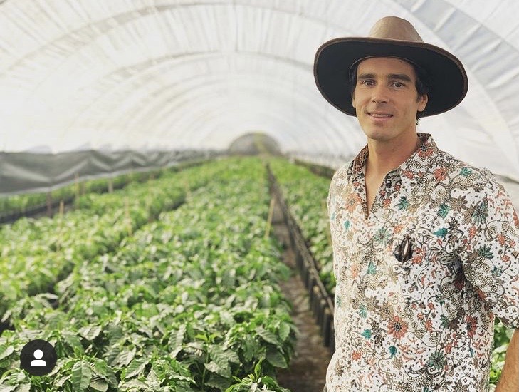 Griffin in a coffee nursery, rows of seedlings behind him